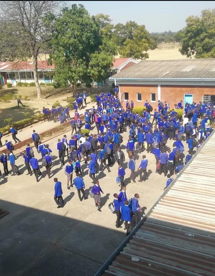 Students in blue uniforms gathered between the school buildings