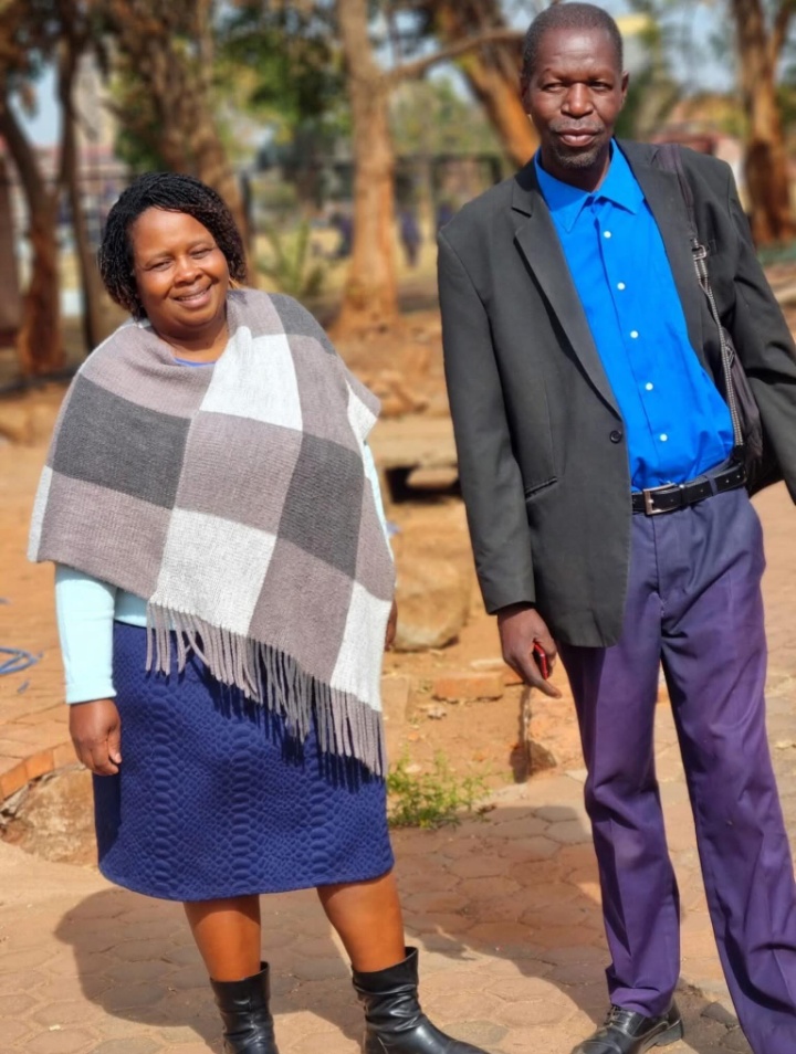 Two adults standing together outdoors on the school grounds
