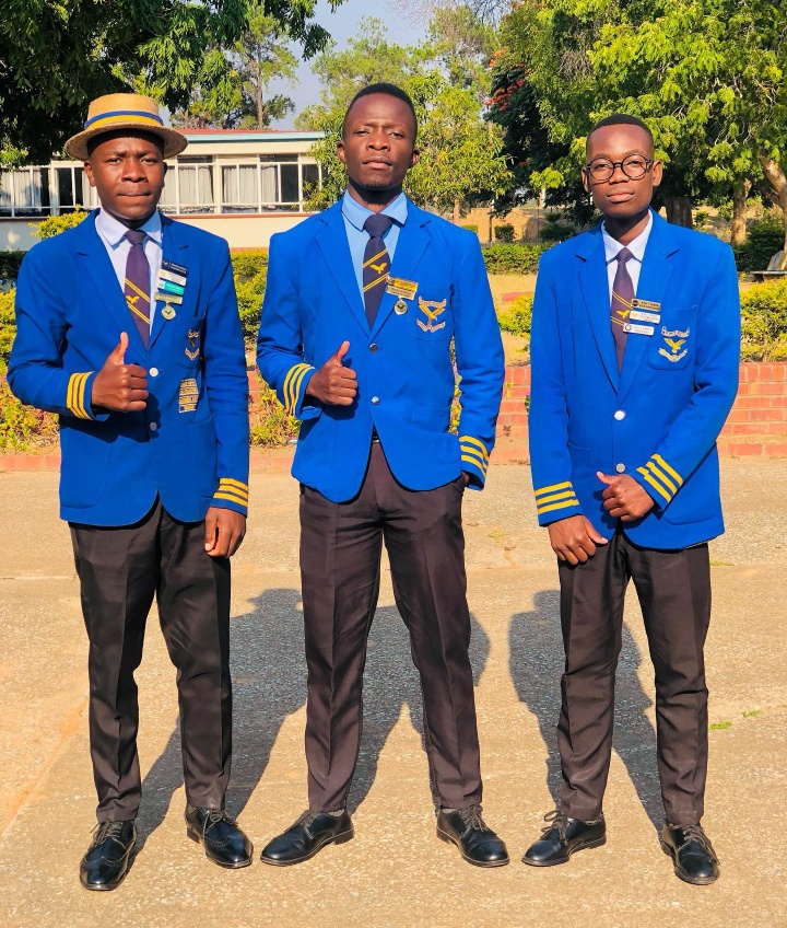 Three students in blue school blazers standing on campus