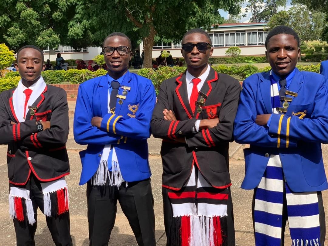 Four students wearing school blazers and scarves on campus